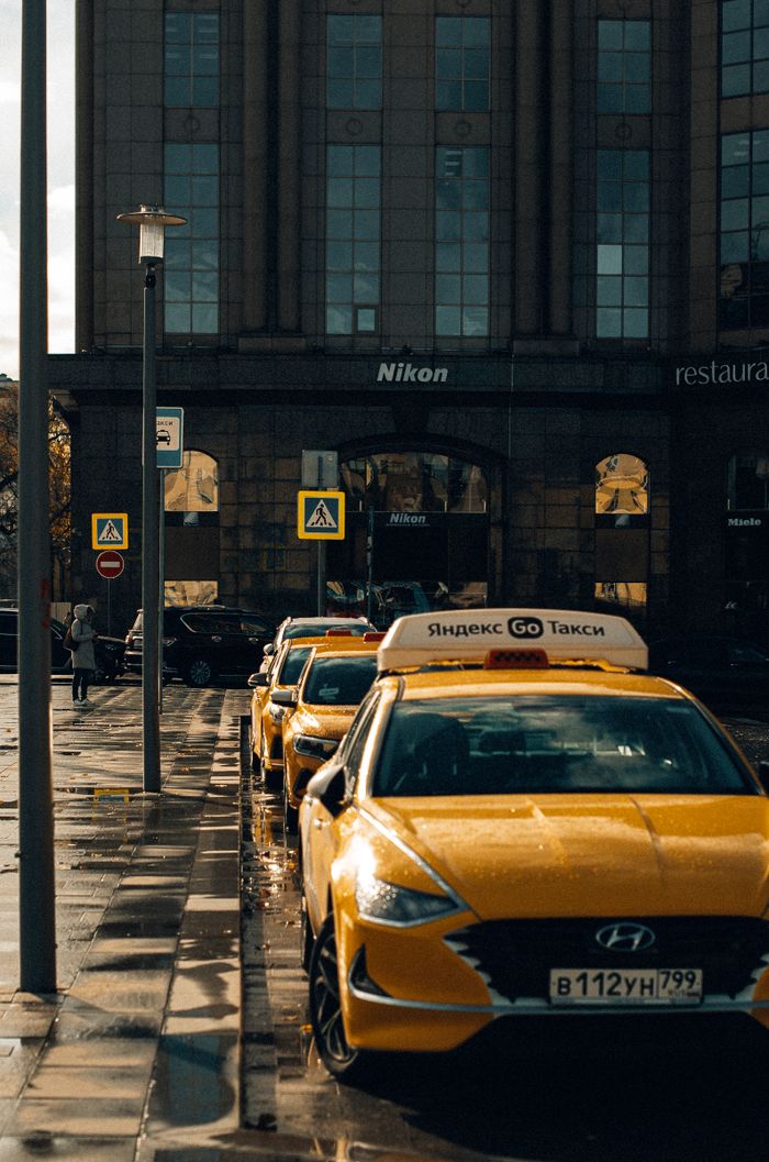 services-02 Urban scene featuring parked yellow taxis on a city street in front of a building on a rainy day.