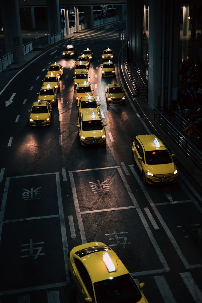 services-04 High angle view of lined yellow taxis on urban street during nighttime.